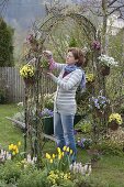 Frühlingsblüher in Töpfen an Rosenbogen gehängt