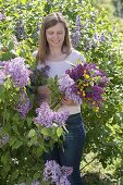 Woman with fragrant bouquet of Syringa (lilac) and Ranunculus acris