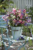 Bouquet of aquilegia (columbine) and grasses in enameled bucket