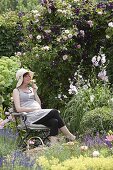 Pregnant woman enjoying the scent in the rose garden