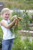 Girl with freshly harvested carrots (Daucus carota)
