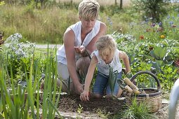 Mother and daughter sowing spinach in the vegetable patch