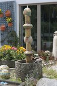 Pillar of pottery elements as water feature in granite tub