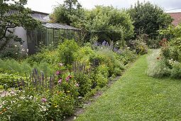 Colourful bed with summer flowers, perennials, vegetables and herbs
