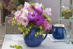 Bouquet of Gladiolus (gladioli) and Humulus (hops) in blue pitcher