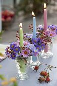 Candle jars with aster (autumn asters) and rose (rose hips) in a row