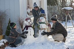 Familie baut Schneemann auf der Terrasse
