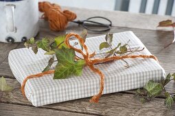 Book gift-wrapped in tea towel with orange string and tendril