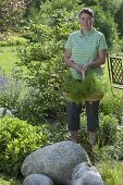 Frau pflanzt Sommerblumen ins Beet