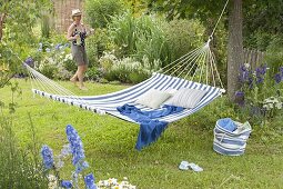 Suspended hammock between trees, bed with perennials and grasses