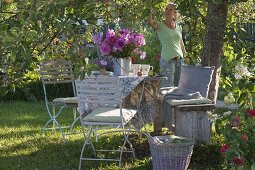 Set table under apple tree with bouquet of summer flowers