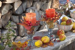 Herbstliche Kerzendeko mit Blättern, Rosa (Hagebutten) und Chaenomeles