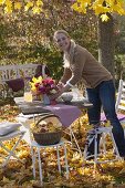 Family at table in golden autumn leaves under maple tree