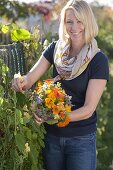 Frau pflückt Strauss von Sommerblumen mit essbaren Blüten