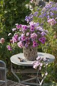 Roses, pink autumn bouquet of aster (white wood aster) in basket vase