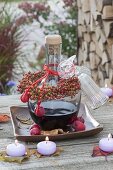 Bottle of red wine liqueur as a gift with a rosehips bouquet