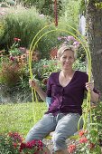 Hanging armchair on the tree, flower beds with summer flowers and perennials