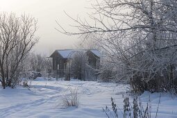 Spur durch den verschneiten Garten, Blick auf Teehaus mit Rosenbogen