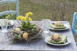 Ostertischdeko mit Kranz aus Zweigen, Gräsern und gelber Primel