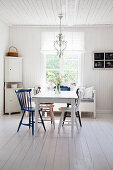 Windsor chairs in various colours around table in bright dining room