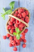 Raspberries in a basket on a blue wooden background