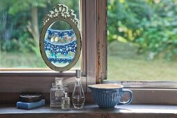 Earrings hung from crocheted trim in oval picture frame in front of window