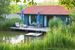 Haus am See mit Terrasse über dem Wasser und Badeplattform