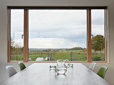 View of landscape through large window across dining table