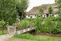 Traditional Frisian 17th-century farmhouse with wooden bridge over stream