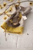 Linen napkin and cutlery decorated with flowering branches of witch hazel (Hamamelis)