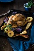 A whole roast chicken with parsnips, roasted onions and apples