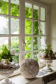 Arrangement of plants and stone ball on sill of lattice window
