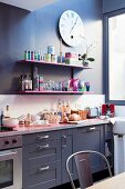 Pink shelves on dark wall between wall clock and worksurface