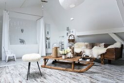 Fur blankets and wooden sledge in rustic lounge area of modern bathroom