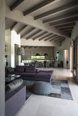 Persian rug in shades of grey and sofa set in open-plan interior with white-painted wooden ceiling