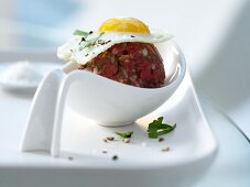 Beef stew in a spoon with a quail egg