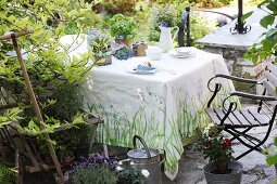 Painted tablecloth and jug vase on table on garden terrace