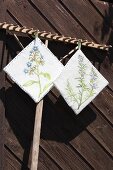 Hand-made pot holders with painted and embroidered floral motifs run from wooden rake