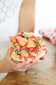 A woman holding a small strawberry pizza