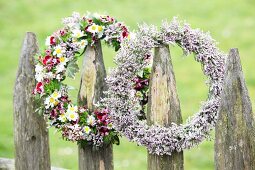 Two flower wreaths hung from rustic garden fence