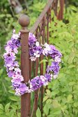 Heart-shaped wreath of hydrangea and phlox flowers on rusty garden fence
