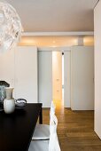 View past dining table to wall with sliding doors, transom window and fitted cupboards