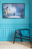 Black designer chair against turquoise wall