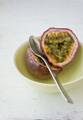 Passion fruit, halved, in a bowl with a spoon