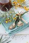 Silver spoons and sprigs of sea buckthorn on napkin