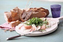 Mairübchen-Carpaccio mit Schinken, Pilzen und Rucola serviert mit Stangenbrot