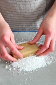 A block of marzipan being kneaded on icing sugar
