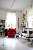 weiße Polsterbank und roter Sessel im Arbeitszimmer mit Bücherregalen