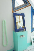 Blue-framed mirror on mint-green cabinet