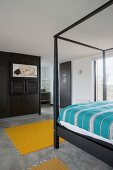 Black bed frame and partition in bedroom with concrete floor